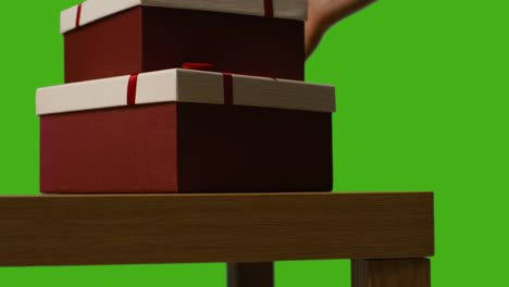 Nahaufnahme-Eines-Mannes,-Der-Verpackte-Geschenke-In-Schachteln-Vom-Tisch-Aufhebt,-Aufgenommen-Vor-Einem-Greenscreen